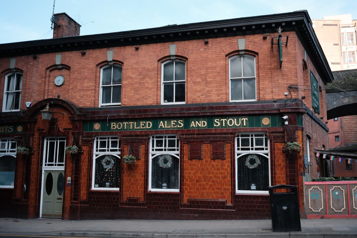 Traditional red brick English pub exterior with signage for cask ales and stout